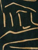Close-up of a dark green rug with gold abstract patterns